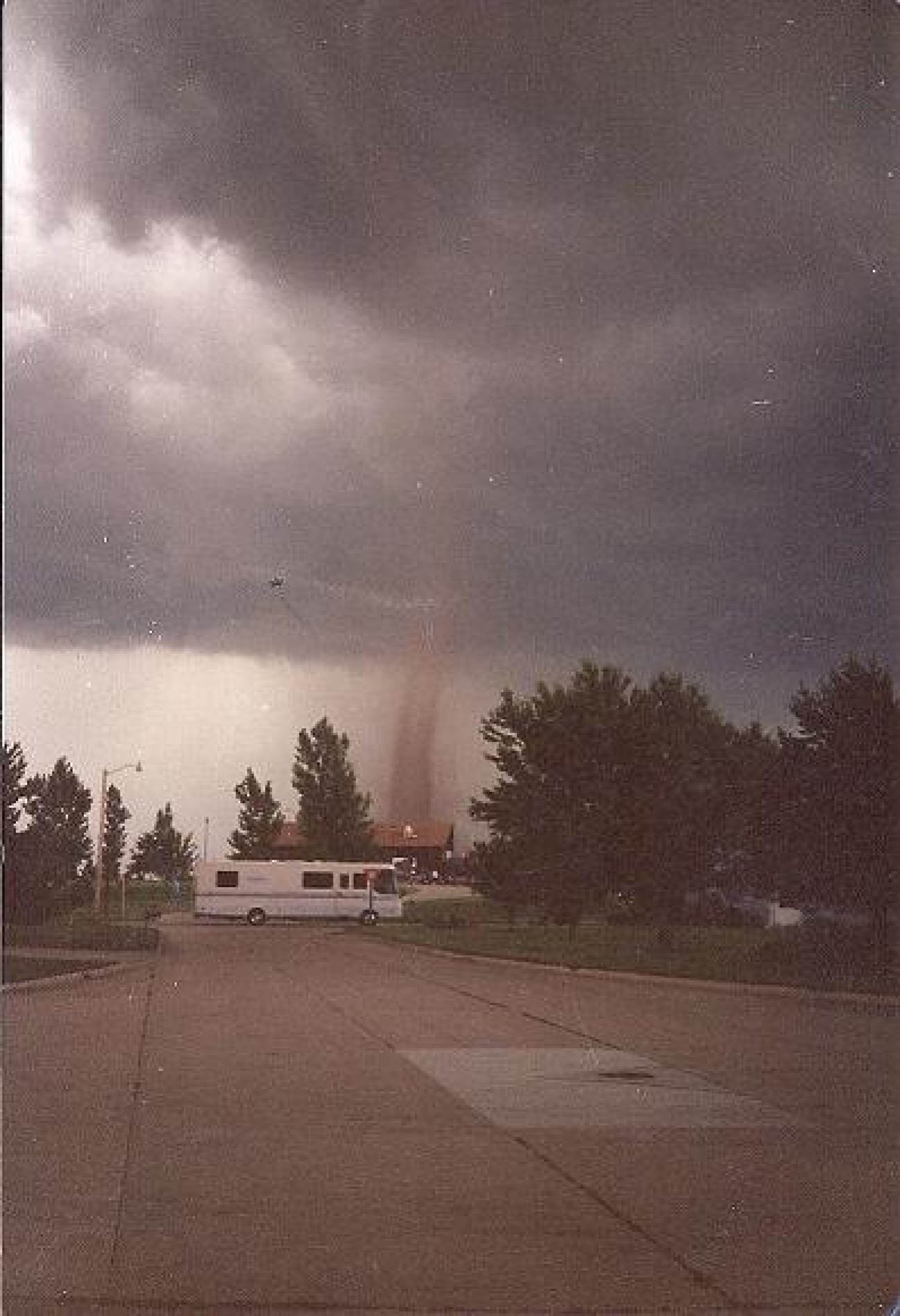 The tornado's condensation funnel behind an evacuating vehicle. 
